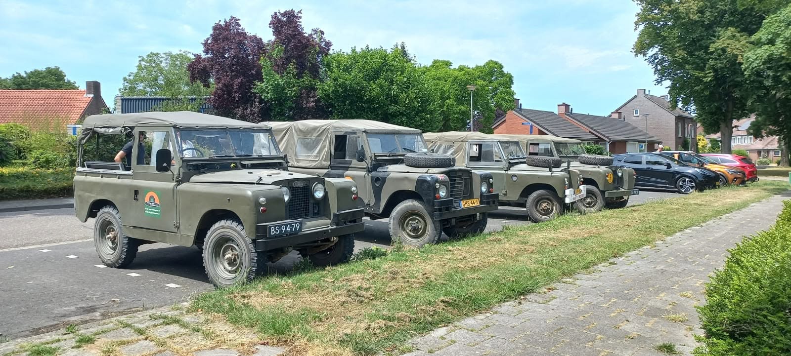 Five classic Land Rovers parked along the road