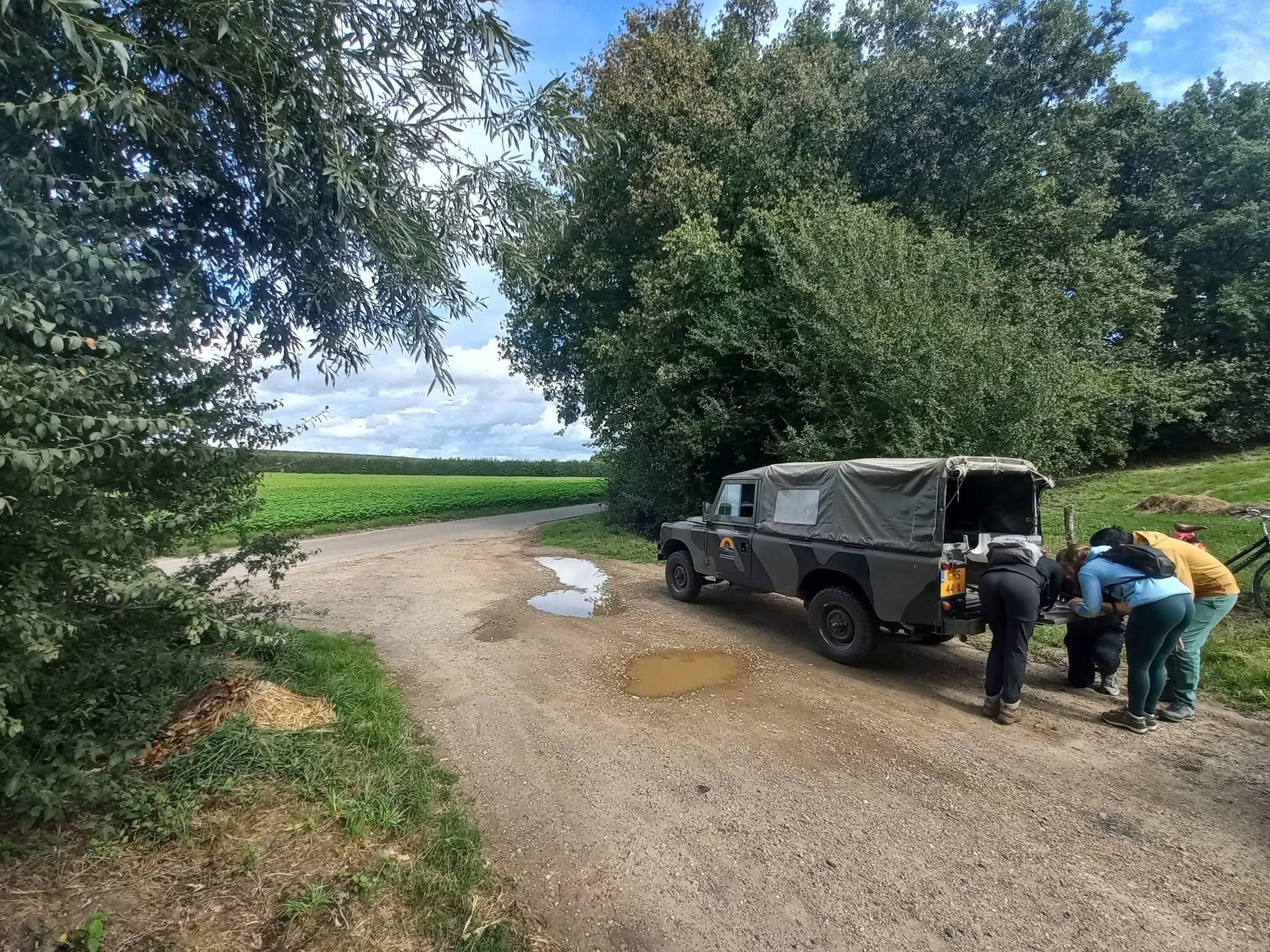Land Rover Series 3 109 GHS-44-X langs een landweg met bezoekers bij de achterzijde
